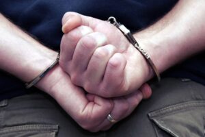 A person handcuffed due to being accused of sex crime.