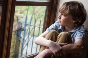 A child sad and looking out the window.